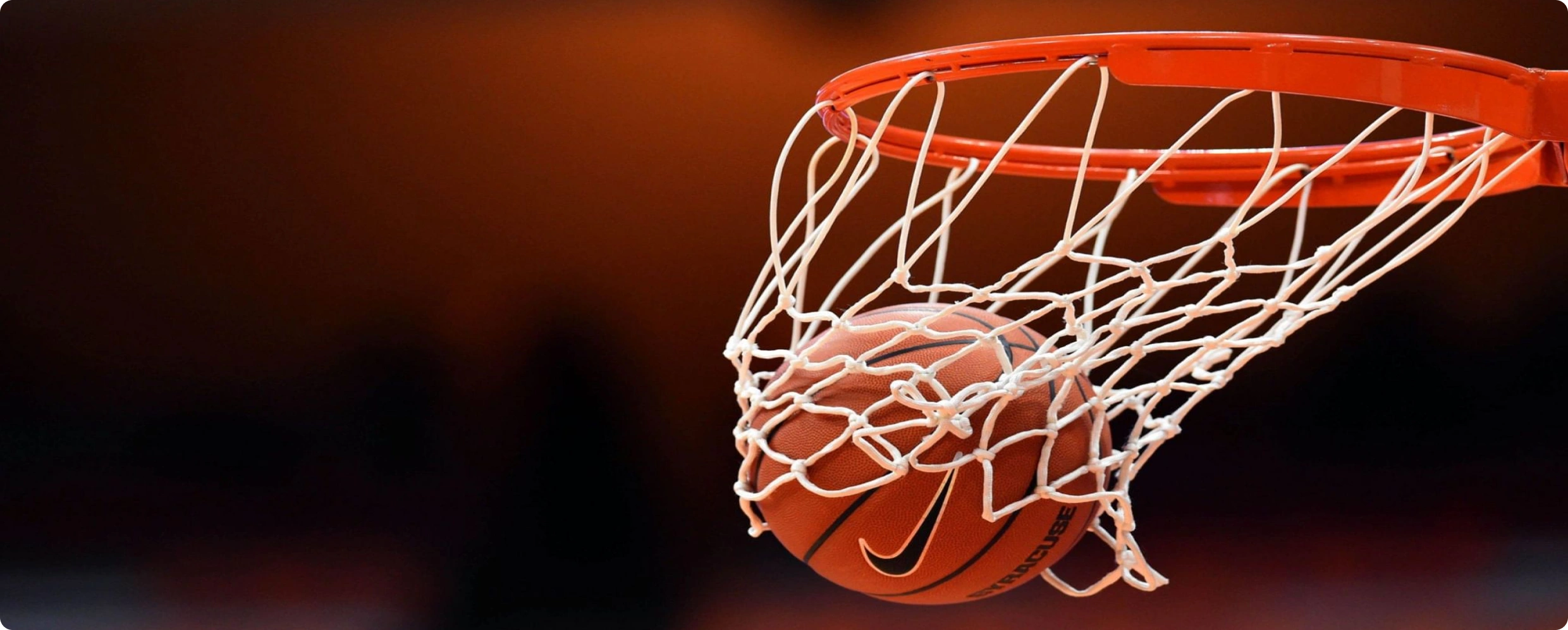 Basketball players contesting a shot at the hoop during an indoor tournament game