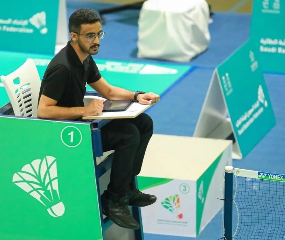 Судья ведёт счёт матча на планшете у корта на турнире Saudi Badminton Federation